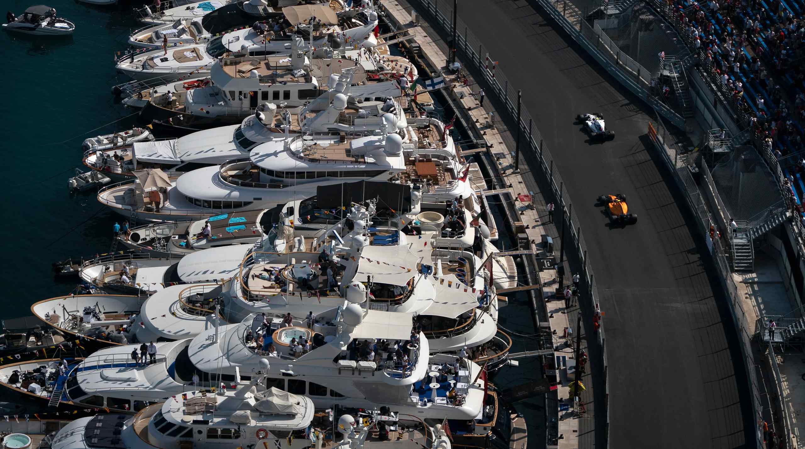 Race cars zooming passed docked yachts in Monaco.